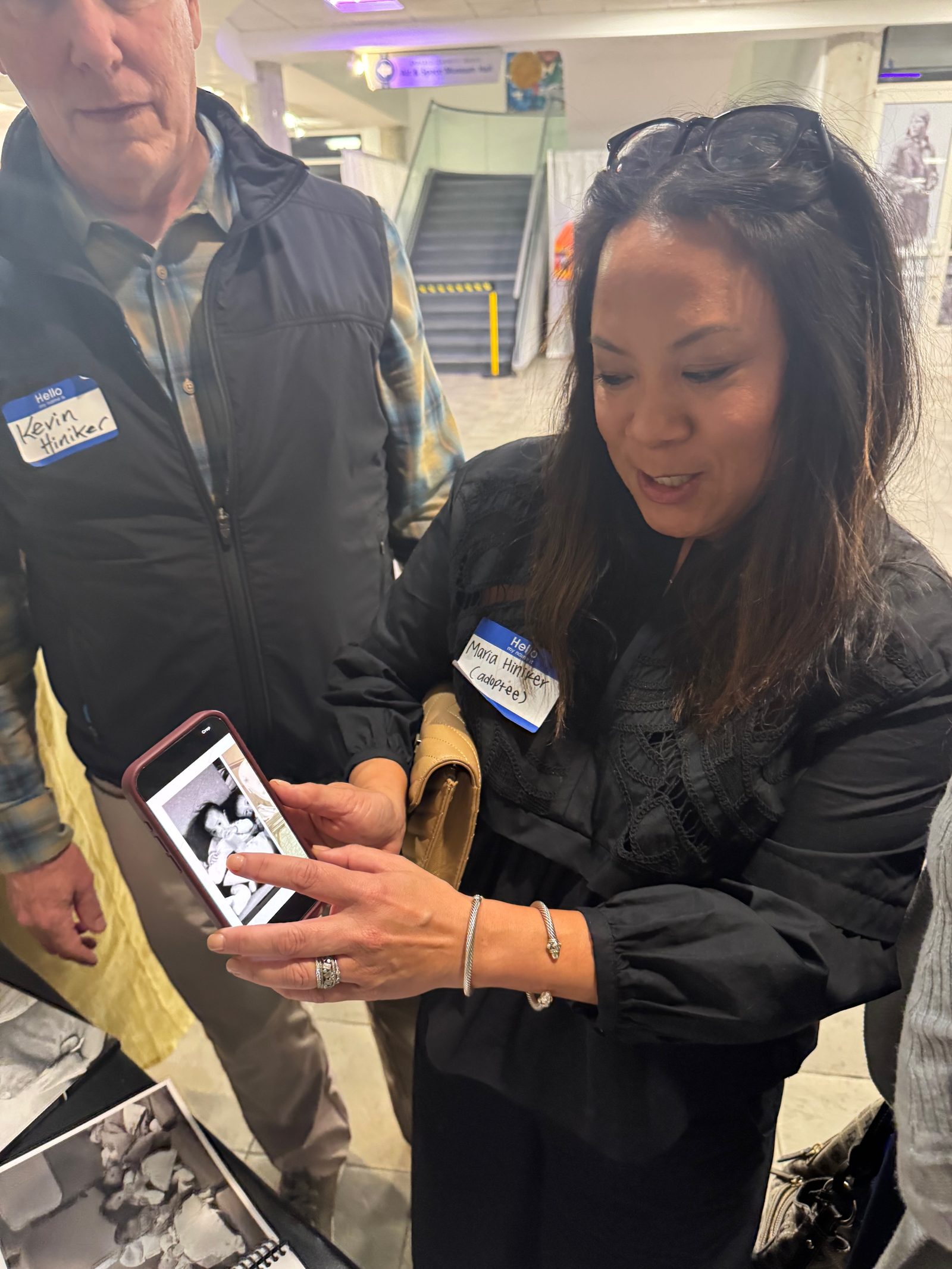 An adoptee showing a phone photograph of her found family at an Operation Babylift gathering
