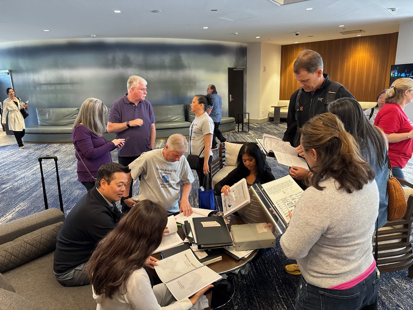 Adoptees and community members gathered around a table exploring archival binders and records