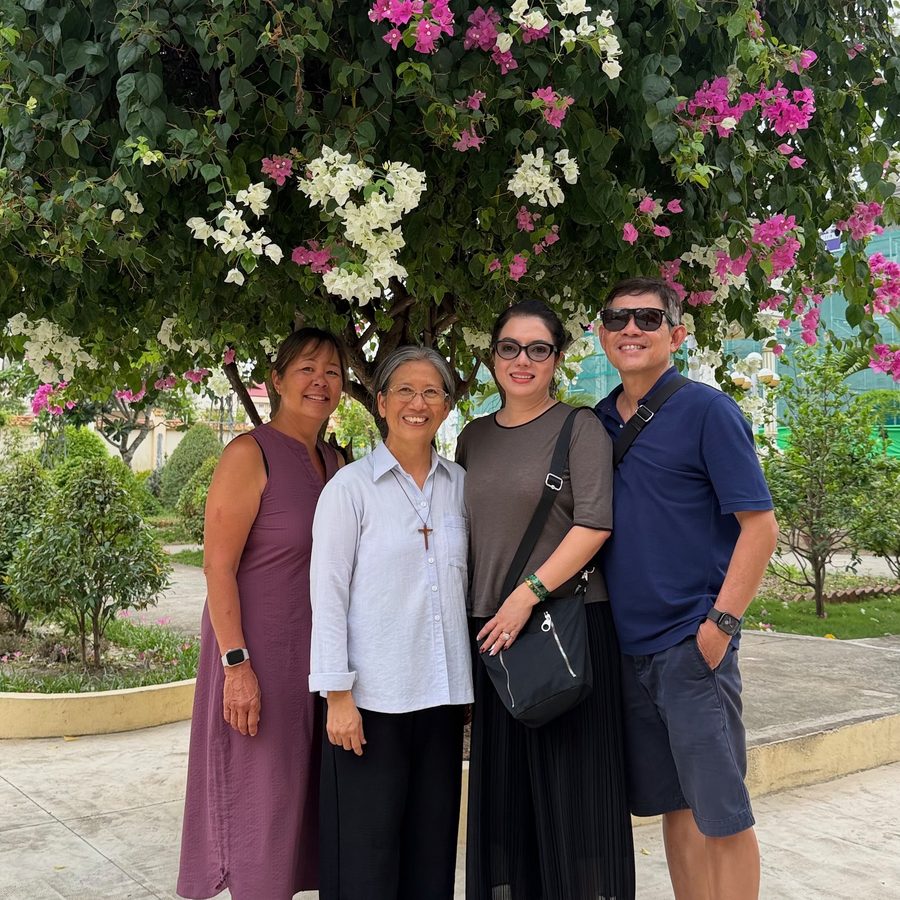 Devaki with a Vietnamese sister and two others standing beneath a flowering bougainvillea tree