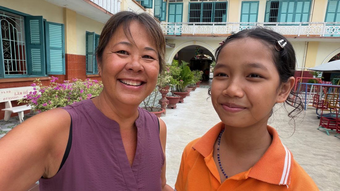 Devaki with a young girl in an orphanage courtyard in Vietnam